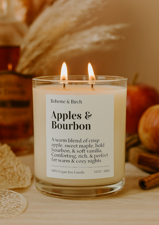Candle labeled 'Apples & Bourbon' by Boheme & Birch on a wooden surface with autumnal decorations.